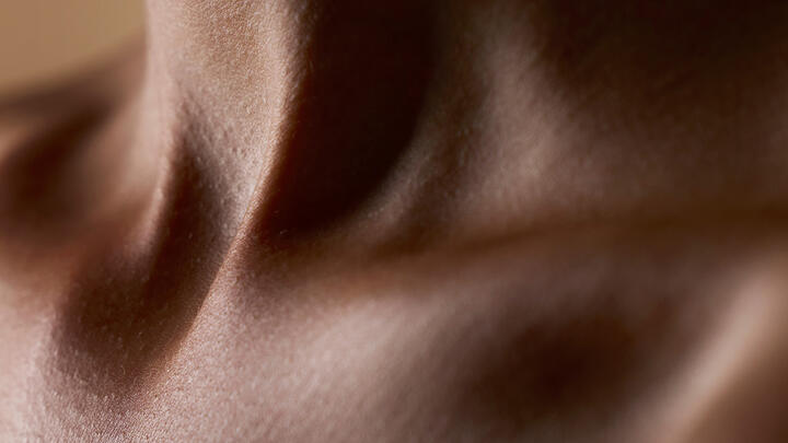 A closeup of an African-American young woman's neck with healthy skin and a beutiful play of light and shadow 